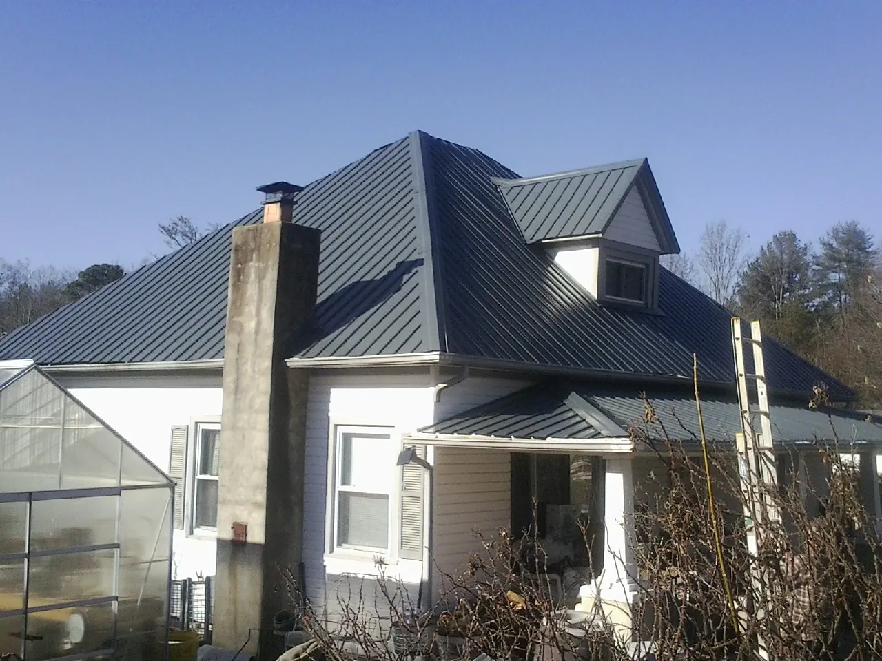 Dark blue standing seam metal roof on a white farmhouse with dormer — Slate & Tile Roof Repair by Roofing Brothers in White Post