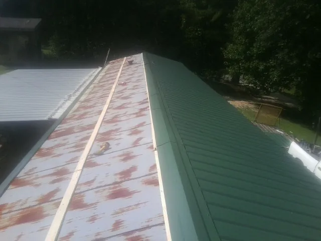 Old rusted panels beside newly installed green metal roofing — Wind Damage Roof Repair by Roofing Brothers in White Post