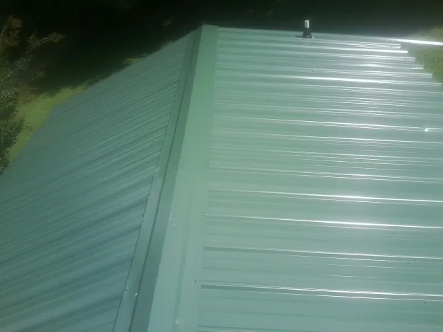 New green metal panels meeting at the ridge of a roof — Flat Roof Repair work by our crew in White Post