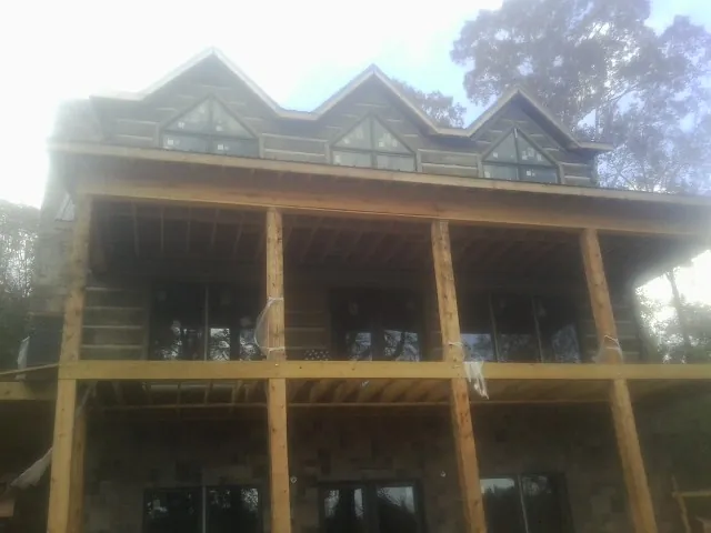Dormers and porch framing on a large log home under construction — Roof Coating work by our crew in White Post