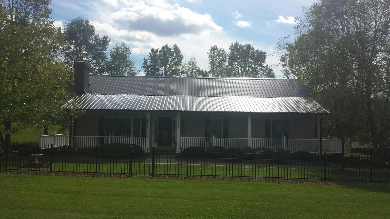 Gray metal roof on a brick ranch with a full width front porch — Gutter Guard Installation work by our crew in White Post