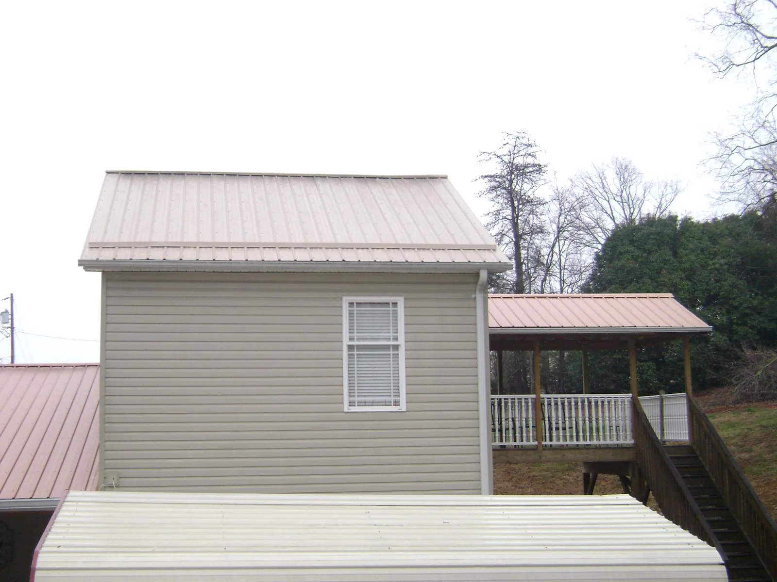 Tan metal roofs on a two story addition and attached porch, from a Roof Replacement job in White Post